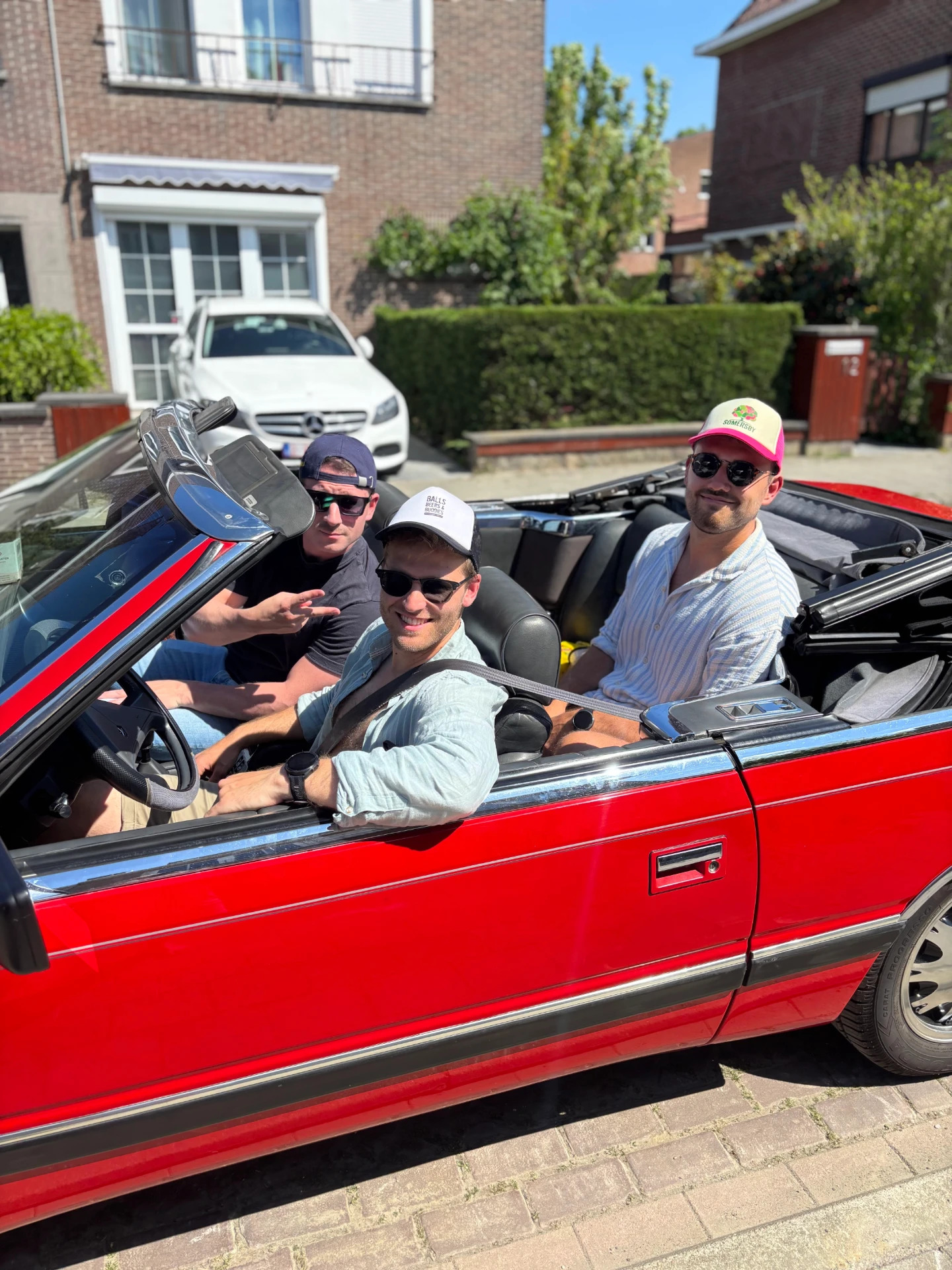 Drie vrienden met zonnebril in de rode cabrio